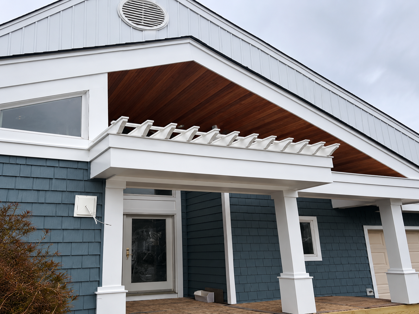 Finished cedar porch ceiling and pergola on a blue-shingle home